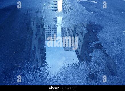 Pop Art Style edifici alti di colore blu dopo la pioggia che riflette Sul Puddle Foto Stock