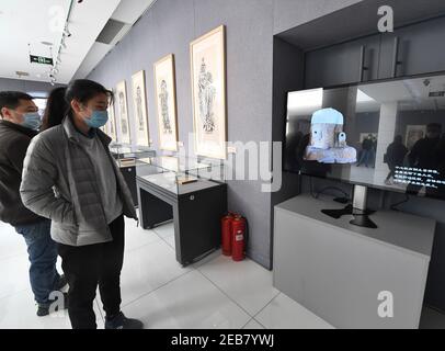 (210212) -- PECHINO, 12 febbraio 2021 (Xinhua) -- i visitatori guardano un video che presenta le grotte di Tianlongshan e le reliquie culturali in esso durante una mostra al Luxun Museum di Pechino, capitale della Cina, 12 febbraio 2021. Una testa di Buddha di pietra che è stata rubata dalla Cina quasi un secolo fa e recentemente recuperata è apparsa in una mostra al Museo Luxun di Pechino a partire da Venerdì, che è il cinese Lunar New Year. La testa del Buddha appartiene a una delle numerose statue di pietra nelle grotte di Tianlongshan, nella città di Taiyuan, nella provincia di Shanxi. Era la centesima reliquia recuperata da C. Foto Stock