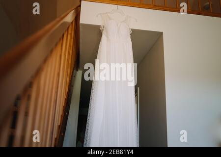 foto di un abito da sposa appeso in camera Foto Stock