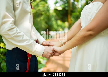 tema di nozze, tenendo le mani sposi novelli in caldo giorno d'estate Foto Stock