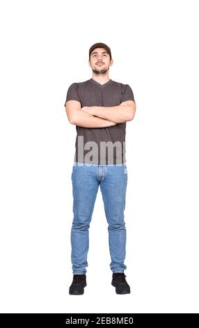 Un dipendente uomo sicuro a tutta lunghezza, mantiene le braccia incrociate, guardando avanti isolato su sfondo bianco. Cuffia da uomo e abbigliamento casual Foto Stock