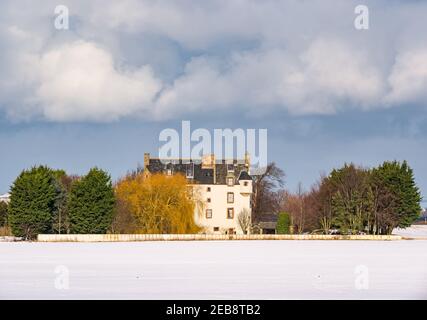 East Lothian, Scozia, Regno Unito, 12 febbraio 2021. Regno Unito Meteo: Ballencrieff House, una casa in stile baronale scozzese fortificato circondata dalla neve in inverno con un cielo tempestoso Foto Stock