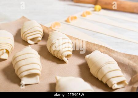 Croissant crudi con frutta pronta per essere cotti su vassoio con carta da forno. Foto Stock