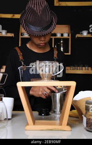 Il barista indonesiano prepara bevande al caffè per i clienti. Ritratto di un dipendente del bar che prepara il caffè al bar. Il processo di Foto Stock