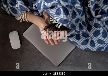 Donna coperta da una plaid si addormentò sul portatile, era stanca di lavoro e decise di riposare. Foto Stock