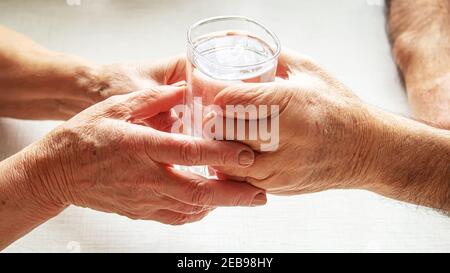 Nonna dà un bicchiere d'acqua al nonno. Fuoco selettivo. Cibo. Foto Stock