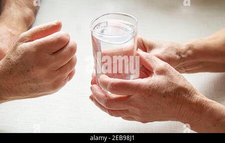 Nonna dà un bicchiere d'acqua al nonno. Fuoco selettivo. Cibo. Foto Stock