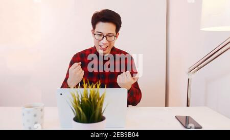 Giovane ragazzo asiatico eccitato sentirsi felice dopo avere ottenuto l'intervista di lavoro in linea. Foto di alta qualità Foto Stock