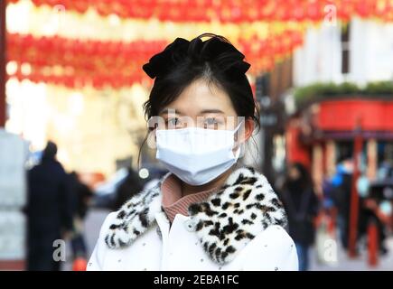 Londra, Regno Unito, 12 febbraio 2021. Lanterne tradizionali per le celebrazioni del Capodanno cinese a China Town, Soho, Londra, Regno Unito. Elegante e mascherata donna cinese ha coraggiato il freddo per una passeggiata intorno alla zona, per l'inizio dell'anno dell'Ox. Monica Wells/Alamy Live News Foto Stock