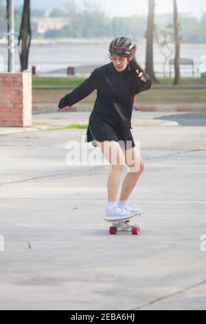 Donne asiatiche su skates bordo all'aperto nella bella giornata estiva. Le giovani donne felici giocano a surfskate al parco l'ora del mattino. Attività sportive stile di vita conce Foto Stock