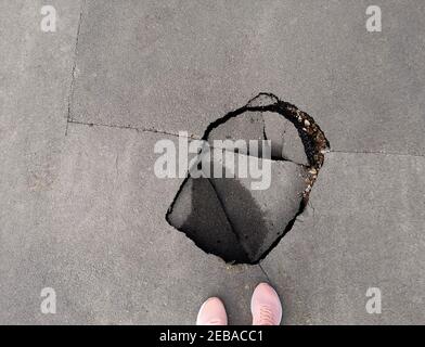 Un buco nella strada. Buca nell'asfalto. Strada rotta. Strada asfaltata danneggiata Foto Stock