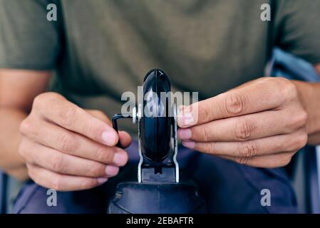 closeup di un giovane caucasico, con una t-shirt verde e pantaloni grigi, sostituendo le ruote di un pattino inline, utilizzando una chiave esagonale Foto Stock