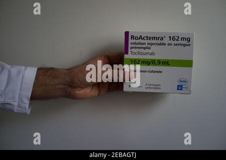 Mano che tiene Tocilizumab, Roactemra farmaco scatola, artrite farmaco utilizzato nel trattamento di Covid-19 Foto Stock