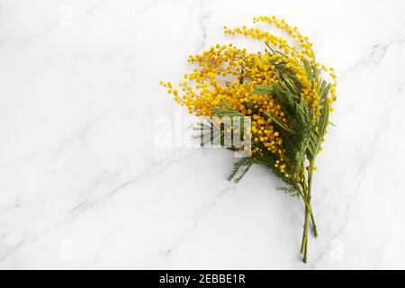un bouquet di fiori di mimosa gialli su sfondo marmoreo. Concetto di giorno delle donne o delle madri. Foto Stock