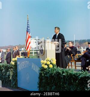 Viaggio nel Maine u0026 Massachusetts: Maine, Orono, Indirizzo presso l'Università del Maine/Orono, 11:00. Il presidente John F. Kennedy (a Lectern) fa le sue osservazioni durante la convocazione all'Università del Maine di Orono. Seduto sul palco: Senatore Edmund S. Muskie del Maine (prima fila); Registrar e Direttore dei servizi agli studenti, George H. Crosby (seconda fila). White House Secret Service Agent, Arthur L. u201cArtu201d Godfrey, e altri si trovano a sinistra della piattaforma. Alumni Memorial Athletic Field, Orono, Maine. Foto Stock