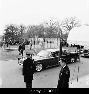 Cerimonia di arrivo per Jorge Alessandri Rodru00edguez, Presidente del Cile, 11:15. Cerimonie di arrivo per il presidente del Cile, Jorge Alessandri Rodru00edguez; il presidente John F. Kennedy e il presidente Alessandri Rodru00edguez (nascosto), siedono nella sede posteriore della limousine presidenziale (Lincoln-Mercury Continental convertibile con tettuccio a bolla), prima di partire per Blair House. Guardie militari d'onore e guardie di colore stanno all'attenzione sul prato del sud. Portico Sud, Casa Bianca, Washington, D.C. Foto Stock