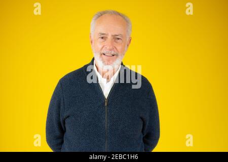 Volto di bell'uomo anziano che indossa giacca blu isolato su sfondo giallo Foto Stock
