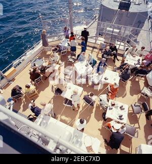 Il presidente Kennedy si accuda alla prima gara di Coppa Americau0027s. Il presidente John F. Kennedy e la First Lady Jacqueline Kennedy partecipano alla prima gara della Americau0027s Cup 1962 a bordo della USS Joseph P. Kennedy, Jr., al largo della costa di Newport, Rhode Island. Il presidente Kennedy (seduto a sinistra) guarda la corsa; la signora Kennedy (in basso a sinistra) visita con il capo del protocollo, Angier Biddle Duke. Anche nella foto: John Forbes Kerry; Janet Jennings Auchincloss; Franklin D. Roosevelt, Jr.; Nuala Pell, moglie del senatore Claiborne Pell (Rhode Island); Julia Ann Shepard; Naval Aide al presidente, Capitano Tazewell Shepa Foto Stock