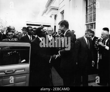 Incontro con Apollo Milton Obote, primo Ministro dell'Uganda, ore 16:03. Il presidente John F. Kennedy stringe le mani con il primo ministro ugandese, A. Milton Obote (a destra della porta dell'auto aperta), alla partenza del primo ministro Oboteu0027s dalla Casa Bianca; fotografi e giornalisti osservano. Anche nella foto: Segretario Generale del Congresso ugandese People0027s, John Kakonge; Ministro della Giustizia dell'Uganda, Grace Ibingira; Ministro delle Finanze e dell'Economia dell'Uganda, James Simpson; fotografo della United Press International (UPI), Frank Cancellare. Ingresso dell'ala ovest, Casa Bianca, Washington, D.C. Foto Stock