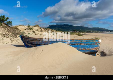 Un relitto colorato di una vecchia barca a remi in legno sepolto La sabbia sulla Playa de Bolonia Foto Stock