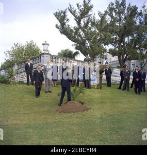 Viaggio a Bermuda: Cerimonia di piantagione di alberi a Government House, Hamilton, Bermuda. Il presidente John F. Kennedy taglia un nastro da un albero appena piantato sui terreni della Government House di Hamilton, Bermuda. In piedi dietro (L-R): Agente del Servizio Segreto della Casa Bianca Ernest u201cErnieu201d Olsson; il Presidente Kennedyu2019s Assistente speciale per la sicurezza nazionale McGeorge Bundy; il Governatore delle Bermuda, il maggiore Generale Sir Julian Gascoigne; Lady Gascoigne (moglie del Governatore); il primo Ministro della Gran Bretagna Harold Macmillan; diverse persone non identificate; Agente di servizio segreto della Casa Bianca William L. u20 Foto Stock