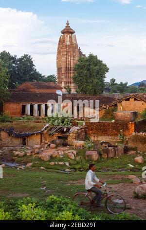 Khajuraho, Madhya Pradesh, India : UN uomo si muove in bicicletta davanti al Tempio di Vamana, parte del gruppo orientale del sito patrimonio dell'umanità dell'UNESCO Khajuraho Foto Stock