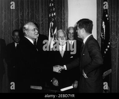 Giuramento in cerimonia, John McCone, Direttore della Central Intelligence Agency (CIA), 11:30. Il presidente John F. Kennedy stringe le mani con il direttore della Central Intelligence Agency (CIA), Allen W. Dulles, in pensione, alla cerimonia di giuramento di John McCone come direttore della CIA. Primo piano (L-R): Dulles, McCone e il presidente Kennedy. In piedi sullo sfondo (L-R): Il senatore Henry M. u201cScoopu201d Jackson (Washington); Glenn T. Seaborg, presidente della Commissione per l'energia atomica (per lo più nascosto da MR. Dulles); e la Corte Suprema degli Stati Uniti, capo di giustizia Earl Warren. Armadio, ho bianco Foto Stock