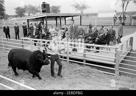 Viaggio in Oklahoma: Il presidente Kennedy con il senatore Robert S. Kerr (Oklahoma) al Kernac Angus Ranch, Poteau, Oklahoma. Il presidente John F. Kennedy visita il senatore dell'Oklahoma Robert Kerr. Senatore Kerr (prima fila, estrema sinistra); presidente Kennedy (prima fila, secondo da sinistra, seduto in sedia a dondolo); Marshall 47 °, senatore Kerru2019 s nero angus bull; altri non identificati. Kermac Angus Ranch, Poteau, Oklahoma. Foto Stock