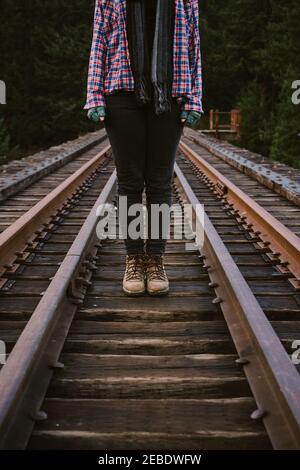 Donna con stivali in pelle e supporti in flanella su binari ferroviari Foto Stock