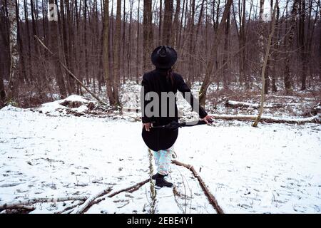 persona trendy in nero tuxedo equilibra lungo il ceppo coperto di neve europa Foto Stock