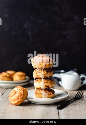 Stack di focaccine di cannella appena sfornate su piatto con sfondo nero. Foto Stock