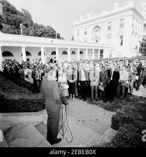 Visita del 1 ° corpo di Pace Volontarii per andare all'estero, 16:10. Il presidente John F. Kennedy parla durante una cerimonia per il primo gruppo di volontari del corpo della Pace in partenza, in partenza per Tanganyika e Ghana, nel Rose Garden, Casa Bianca, Washington, D.C. i giornalisti e i fotografi osservano, compreso il corrispondente di Washington per la Guy Gannet Publishing Company del Maine, May Craig. [Per un elenco completo dei partecipanti, vedere White House Central Subject Files, Box 670, Folder 1: U0022PC 5 Peace Corps Program (Executive, 1-20-61 - 4-10-62).u0022] Foto Stock