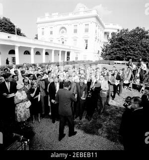 Visita del 1 ° corpo di Pace Volontarii per andare all'estero, 16:10. Il presidente John F. Kennedy saluta i volontari del corpo della Pace durante una cerimonia per il primo gruppo di volontari in partenza, in partenza per Tanganyika e Ghana, nel Rose Garden, Casa Bianca, Washington, D.C. osservatori di giornalisti e fotografi, compreso il corrispondente di Washington per la Guy Gannet Publishing Company del Maine, May Craig. [Per un elenco completo dei partecipanti, vedere White House Central Subject Files, Box 670, Folder 1: U0022PC 5 Peace Corps Program (Executive, 1-20-61 - 4-10-62).u0022] Foto Stock