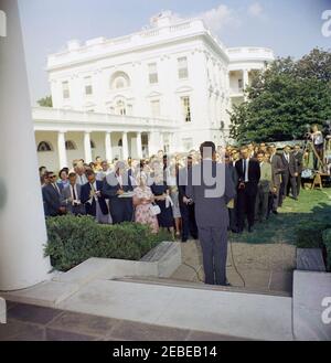 Visita del 1 ° corpo di Pace Volontarii per andare all'estero, 16:10. Il presidente John F. Kennedy parla durante una cerimonia per il primo gruppo di volontari del corpo della Pace in partenza, in partenza per Tanganyika e Ghana, nel Rose Garden, Casa Bianca, Washington, D.C. i giornalisti e i fotografi osservano, compreso il corrispondente di Washington per la Guy Gannet Publishing Company del Maine, May Craig. [Per un elenco completo dei partecipanti, vedere White House Central Subject Files, Box 670, Folder 1: U0022PC 5 Peace Corps Program (Executive, 1-20-61 - 4-10-62).u0022] Foto Stock