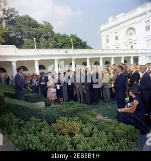 Visita del 1 ° corpo di Pace Volontarii per andare all'estero, 16:10. Il presidente John F. Kennedy parla durante una cerimonia per il primo gruppo di volontari del corpo della Pace in partenza, in partenza per Tanganyika e Ghana, nel Rose Garden, Casa Bianca, Washington, D.C. i giornalisti e i fotografi osservano, compreso il corrispondente di Washington per la Guy Gannet Publishing Company del Maine, May Craig. [Per un elenco completo dei partecipanti, vedere White House Central Subject Files, Box 670, Folder 1: U0022PC 5 Peace Corps Program (Executive, 1-20-61 - 4-10-62).u0022] Foto Stock