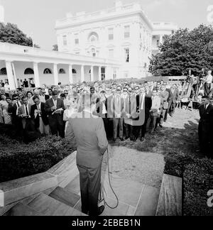 Visita del 1 ° corpo di Pace Volontarii per andare all'estero, 16:10. Il presidente John F. Kennedy parla durante una cerimonia per il primo gruppo di volontari del corpo della Pace in partenza, in partenza per Tanganyika e Ghana, nel Rose Garden, Casa Bianca, Washington, D.C. i giornalisti e i fotografi osservano, compreso il corrispondente di Washington per la Guy Gannet Publishing Company del Maine, May Craig. [Per un elenco completo dei partecipanti, vedere White House Central Subject Files, Box 670, Folder 1: U0022PC 5 Peace Corps Program (Executive, 1-20-61 - 4-10-62).u0022] Foto Stock