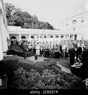 Visita del 1 ° corpo di Pace Volontarii per andare all'estero, 16:10. Il presidente John F. Kennedy parla durante una cerimonia per il primo gruppo di volontari del corpo della Pace in partenza, in partenza per Tanganyika e Ghana, nel Rose Garden, Casa Bianca, Washington, D.C. i giornalisti e i fotografi osservano, compreso il corrispondente di Washington per la Guy Gannet Publishing Company del Maine, May Craig. [Per un elenco completo dei partecipanti, vedere White House Central Subject Files, Box 670, Folder 1: U0022PC 5 Peace Corps Program (Executive, 1-20-61 - 4-10-62).u0022] Foto Stock