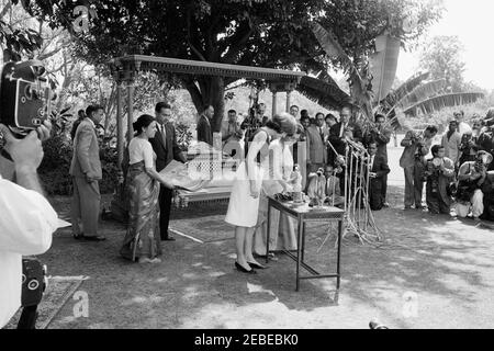 Prima Lady Jacqueline Kennedyu0027s (JBK) viaggio in India e Pakistan: New Delhi, Delhi, India, Childrenu0027s Carnevale d'arte a Teen Murti Bhavan, residenza del primo ministro dell'India Jawaharlal Nehru. First Lady Jacqueline Kennedy presenta il Carnevale d'Arte di Childrenu2019s nel giardino della residenza del primo Ministeru2019s, Teen Murti Bhavan. Nuova Delhi, India. La sig.ra Kennedy sta al tavolo con Indira Gandhi, figlia del primo ministro dell'India Jawaharlal Nehru; il segretario della pressa della Casa Bianca assistente, Jay W. Gildner, si trova in background direttamente dietro la sig.ra Gandhi. La prima Signora ha presentato Th Foto Stock