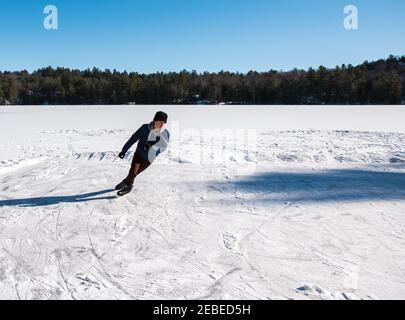 Teen boy pattinaggio su ghiaccio su un lago ghiacciato in un giorno d'inverno in Canada. Foto Stock