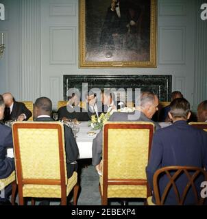 Pranzo in onore di Fulbert Youlou, presidente della Repubblica del Congo (Brazzaville), 13:30. Luncheon in onore del Presidente della Repubblica del Congo Fulbert Youlou (Brazzaville). Il presidente Youlou e il presidente John F. Kennedy sono seduti al centro del tavolo (con un uomo non identificato che si accovacciava tra di loro), e il vice presidente Lyndon B. Johnson è seduto al tavolo terzo da destra con la schiena alla telecamera. Il dipinto sopra il camino è un ritratto del 1869 di Abraham Lincoln di George P. A. Healy e fu donato alla Casa Bianca nel 1939. L'iscrizione nel mar verde Foto Stock