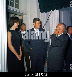 Pranzo in onore del Principe Rainier III e della Principessa Grazia di Monaco, alle 13:00. Partenza degli ospiti dopo un pranzo in onore del Principe Ranier III e della Principessa Grazia di Monaco (attrice Grace Kelly). Il presidente John F. Kennedy e la First Lady Jacqueline Kennedy parlano con un uomo non identificato. L'agente del servizio segreto della Casa Bianca Bill Payne si trova sul bordo destro del telaio. Ingresso dell'ala ovest, Casa Bianca, Washington, D.C. Foto Stock