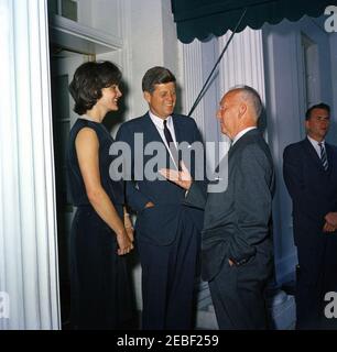 Pranzo in onore del Principe Rainier III e della Principessa Grazia di Monaco, alle 13:00. Partenza degli ospiti dopo un pranzo in onore del Principe Ranier III e della Principessa Grazia di Monaco (attrice Grace Kelly). Il presidente John F. Kennedy e la First Lady Jacqueline Kennedy parlano con un uomo non identificato. L'agente del servizio segreto della Casa Bianca Bill Payne si trova sul bordo destro del telaio. Ingresso dell'ala ovest, Casa Bianca, Washington, D.C. Foto Stock