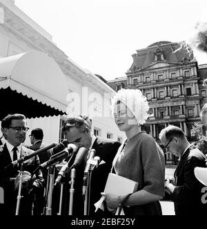 Pranzo in onore del Principe Rainier III e della Principessa Grazia di Monaco, alle 13:00. Il Principe Ranier III e la Principessa Grace di Monaco (attrice Grace Kelly) parlano ai giornalisti dopo aver partecipato a un pranzo in loro onore. I giornalisti osservano, compreso il corrispondente della Casa Bianca per il Columbia Broadcasting System (CBS), George Herman (all'estrema sinistra). All'esterno dell'entrata dell'Ala Ovest, la Casa Bianca, Washington, D.C. Foto Stock