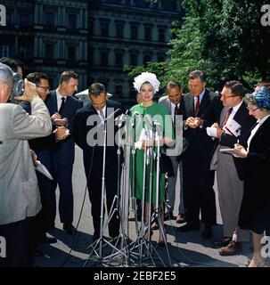 Pranzo in onore del Principe Rainier III e della Principessa Grazia di Monaco, alle 13:00. Il Principe Ranier III e la Principessa Grace di Monaco (attrice Grace Kelly) parlano ai giornalisti dopo aver partecipato a un pranzo in loro onore. I giornalisti osservano, compreso il corrispondente della Casa Bianca per il Columbia Broadcasting System (CBS), George Herman (a sinistra, indossando gli occhiali). All'esterno dell'entrata dell'Ala Ovest, la Casa Bianca, Washington, D.C. Foto Stock