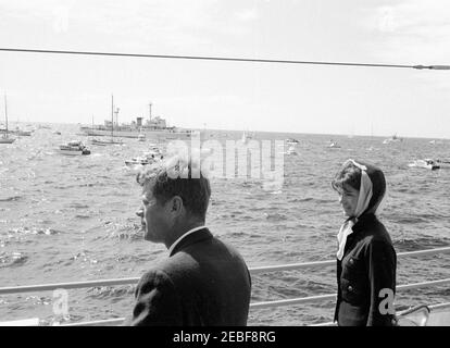 Il presidente Kennedy si accuda alla prima gara di Coppa Americau0027s. Il presidente John F. Kennedy e la First Lady Jacqueline Kennedy guardano la prima gara della Americau0027s Cup 1962 a bordo della USS Joseph P. Kennedy, Jr., al largo della costa di Newport, Rhode Island. Foto Stock