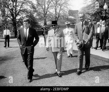 Cerimonia di partenza per Sukarno, Presidente dell'Indonesia, ore 10:40. Il presidente John F. Kennedy e il vice presidente Lyndon B. Johnson camminano con il presidente dell'Indonesia Ahmed Sukarno prima della partenza del presidente Sukarnou2019, South Lawn, White House, Washington, D.C. Foto Stock