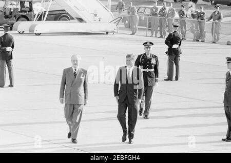 Cerimonie di arrivo per Harold Macmillan, primo ministro della Gran Bretagna, 16:50. Il presidente John F. Kennedy cammina con il primo ministro della Gran Bretagna, Harold Macmillan (a sinistra), durante le cerimonie di arrivo in onore del primo ministro Macmillan. Il comandante delle truppe, il tenente colonnello Charles P. Murray Jr., cammina dietro il presidente Kennedy. Andrews Air Force base, Maryland. Foto Stock