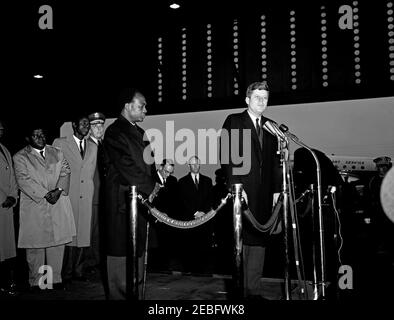 Cerimonia di arrivo per Kwame Nkrumah, presidente del Ghana, 15:43. Il presidente John F. Kennedy ha espresso le sue osservazioni alle cerimonie di arrivo in onore del presidente della Repubblica del Ghana, Osagyefo Dr. Kwame Nkrumah. Da sinistra a destra: Tre uomini non identificati (uno sul bordo dell'immagine); Presidente dei capi di Stato Uniti, Generale Lyman Lemnitzer; Presidente Nkrumah; ufficiale di protocollo per il Dipartimento di Stato, Clemente E. u0022Clemu0022 Conger (sullo sfondo); Capo di protocollo, Angier Biddle Duke; Presidente Kennedy (ai microfoni). Hangar n. 10, Terminal Military Air Transport Service (MATS), Washington National ai Foto Stock