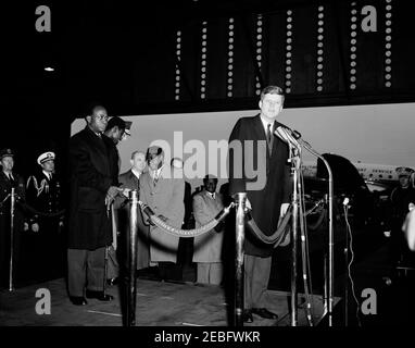 Cerimonia di arrivo per Kwame Nkrumah, presidente del Ghana, 15:43. Il presidente John F. Kennedy ha espresso le sue osservazioni alle cerimonie di arrivo in onore del presidente della Repubblica del Ghana, Osagyefo Dr. Kwame Nkrumah. Da sinistra a destra: Militare Aide al presidente, generale Chester V. Clifton; Naval Aide al presidente, comandante Tazewell Shepard; presidente Nkrumah; uomo non identificato (dietro il presidente Nkrumah); presidente dei capi di Stato congiunti, generale Lyman Lemnitzer (per lo più nascosto); segretario di Stato, Dean Rusk; due uomini non identificati; presidente Kennedy (ai microfoni). Hangar n. 10, Military Air Transpo Foto Stock