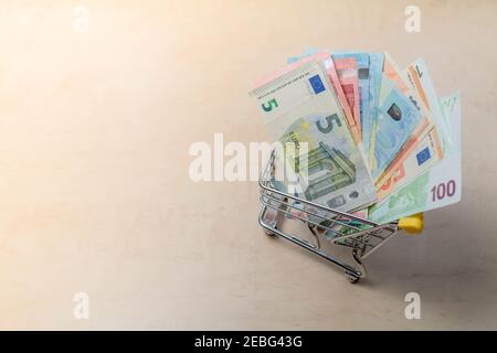 Banconote in euro nel piccolo carrello. Carrello pieno di contanti. Carta denaro. Piccolo carrello della spesa con banconote in euro. E-commerce online. Copia spa Foto Stock